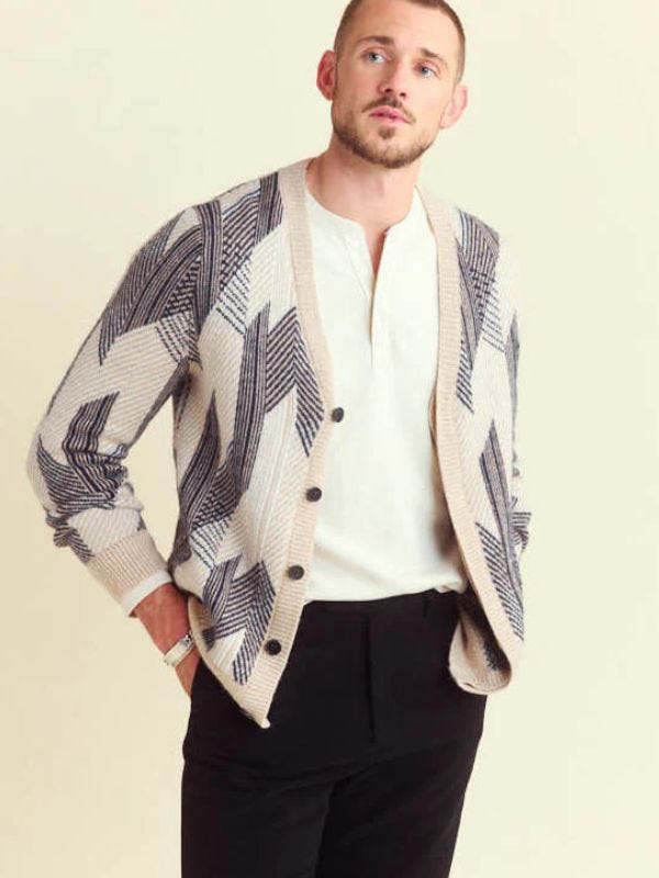 stylish man wearing a jacquard pattern cardigan with a white shirt and black trousers