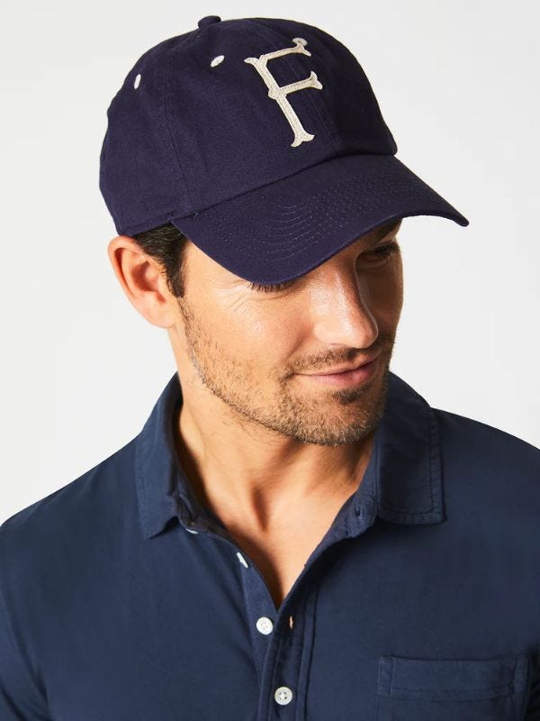 man wearing a baseball cap with the letter F embroidered on the front and a navy polo