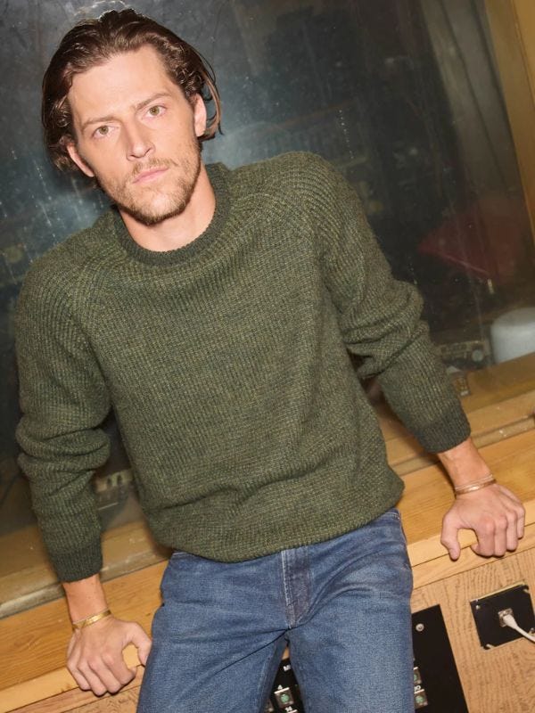 Man wearing green crew neck sweater and jeans