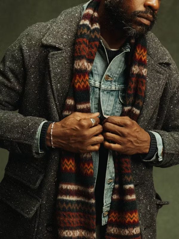 close-up of a man wearing a textured herringbone topcoat over a denim jacket with a Fair Isle scarf