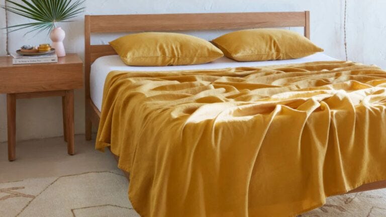 light wood bedframe with yellow sheets and pillows