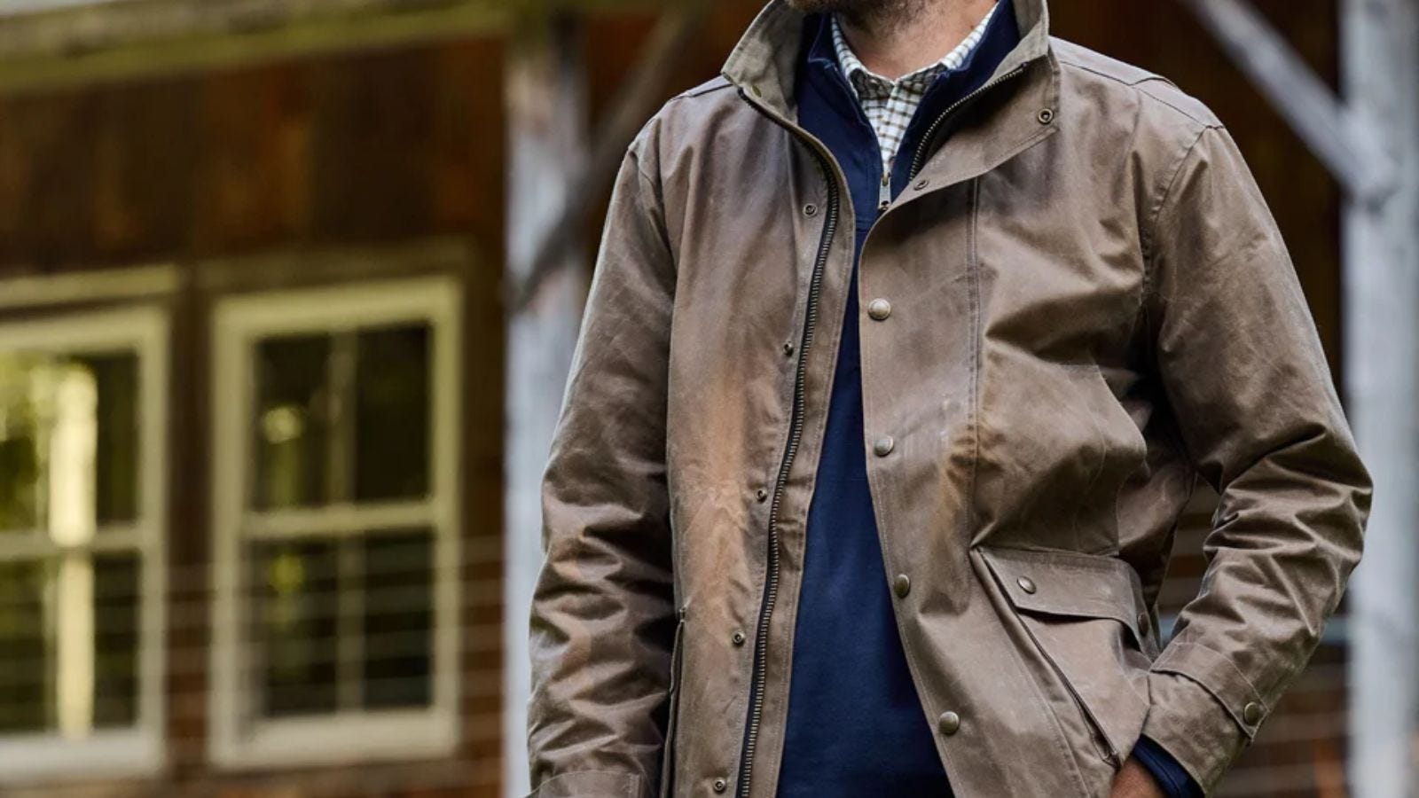 close-up of a man wearing a waxed canvas jacket over a navy sweater