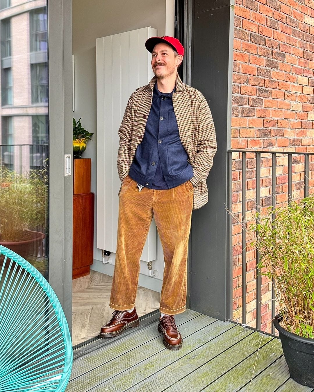 smiling man wearing corduroy pants and a patterned jacket