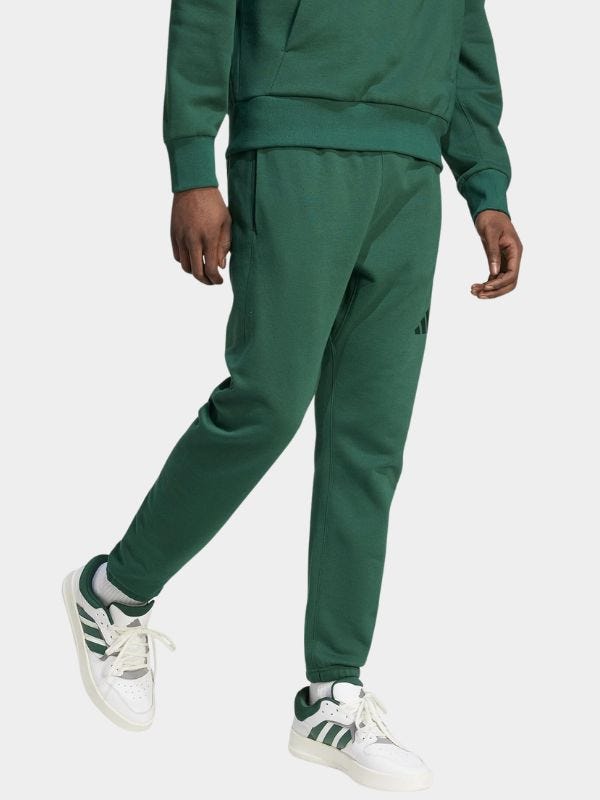 man from the waist down wearing a green sweatsuit and white sneakers with green stripes