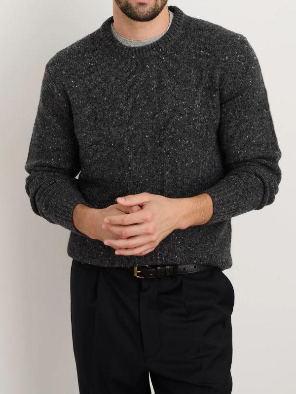 close-up of a man wearing a dark grey sweater and black pants