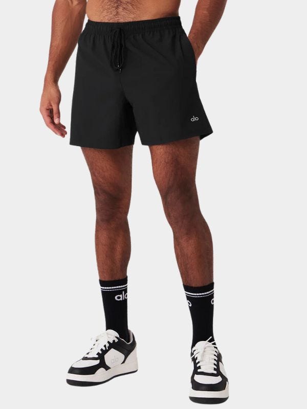 athletically fit man wearing black workout shorts with tall black socks and black and white sneakers