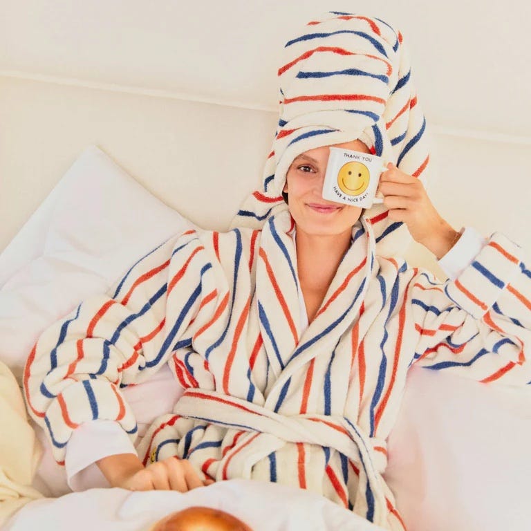 woman wearing a striped robe in bed with a cup of coffee