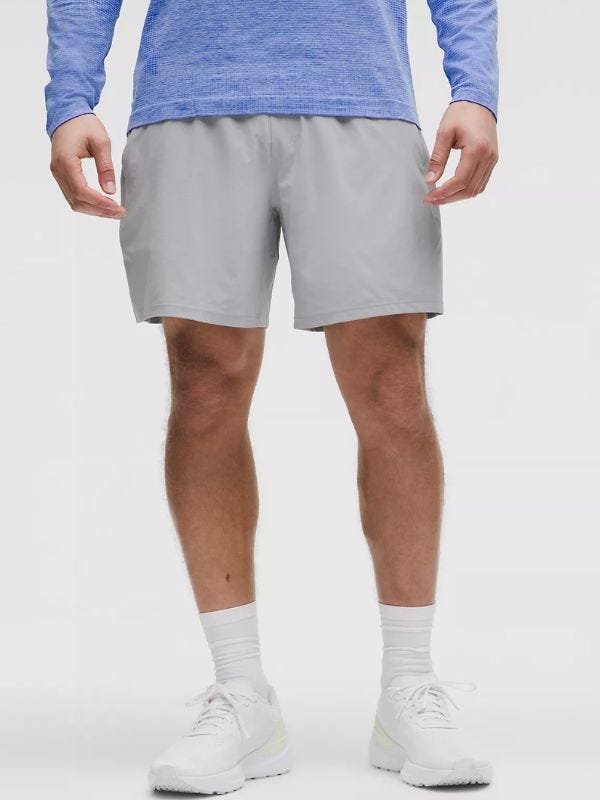 man from the waist down wearing grey performance shorts with tall white socks and white sneakers