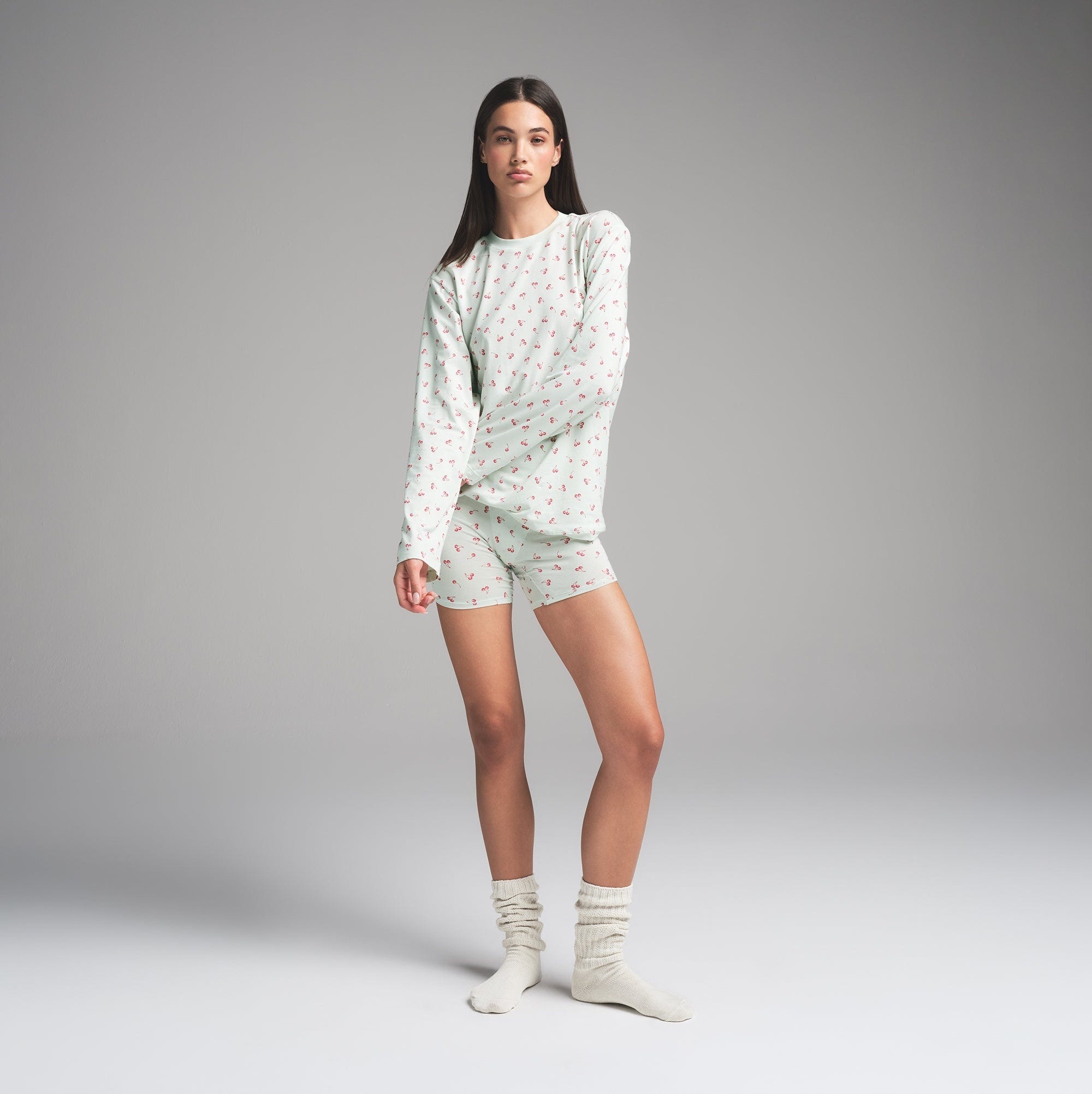 woman in cozy shorts and long-sleeve shirt pajama set with a repeating heart pattern