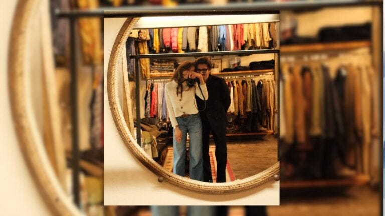 image of couple taking a selfie with a camera in the mirror of a clothing store