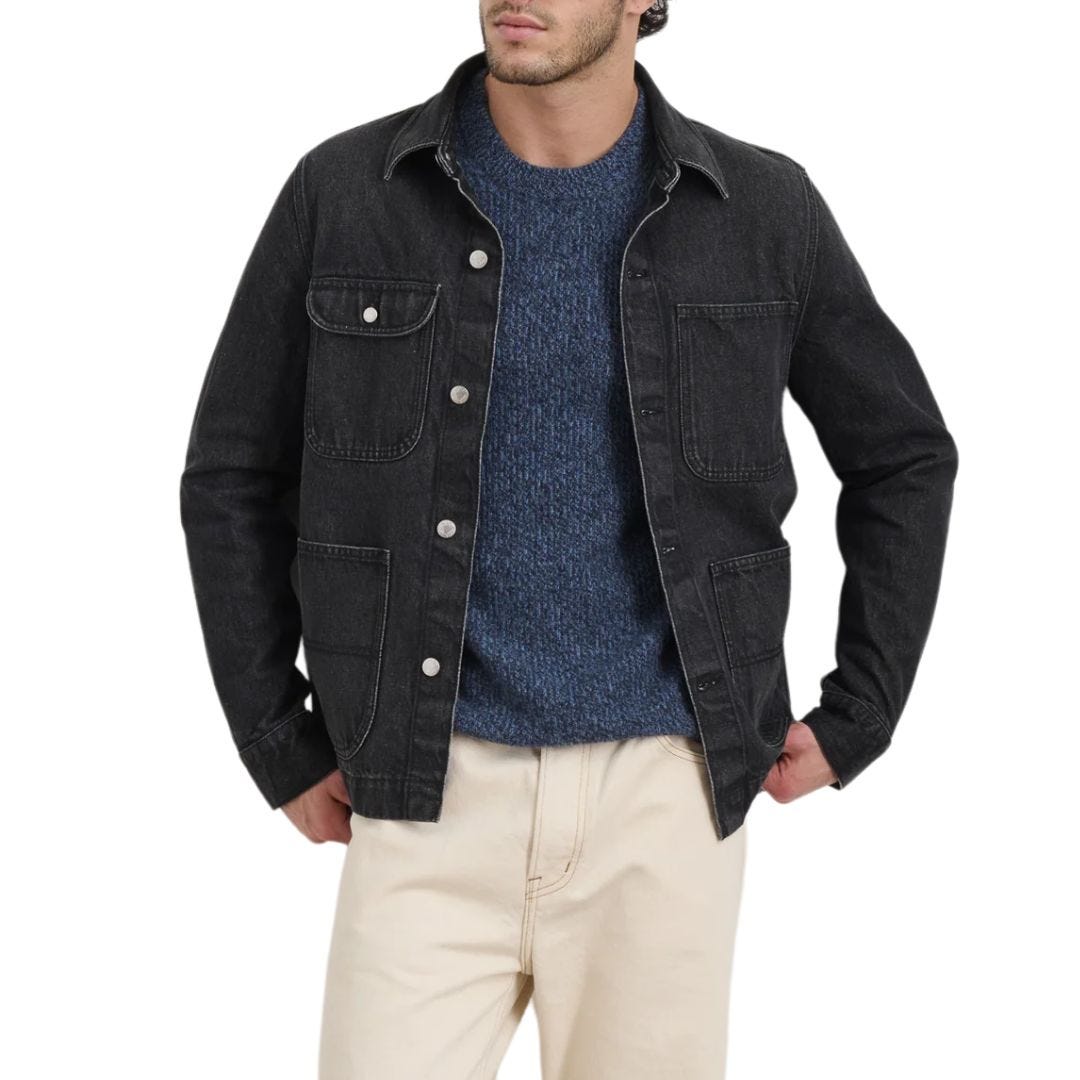 stylish man wearing a black denim chore coat with a navy crewneck sweater and chinos