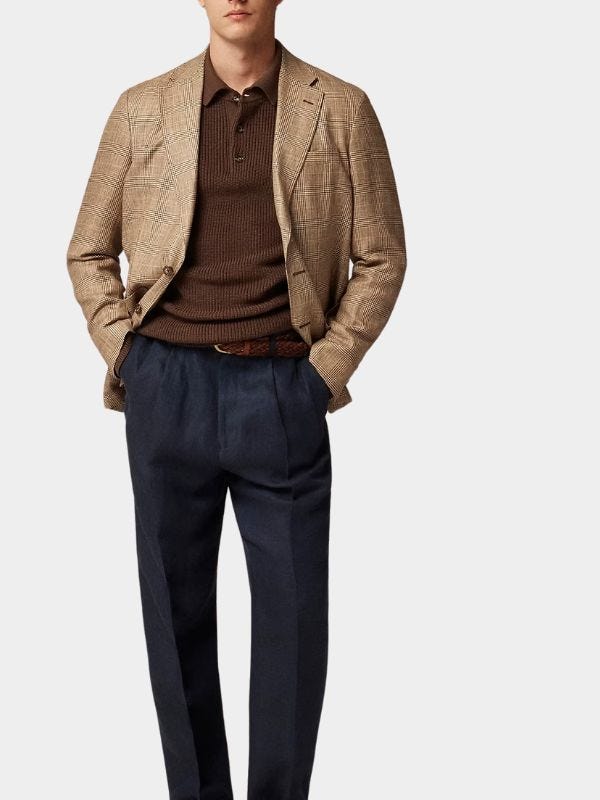 stylish man wearing a brown patterned sport coat over a brown knit polo sweater and navy pants