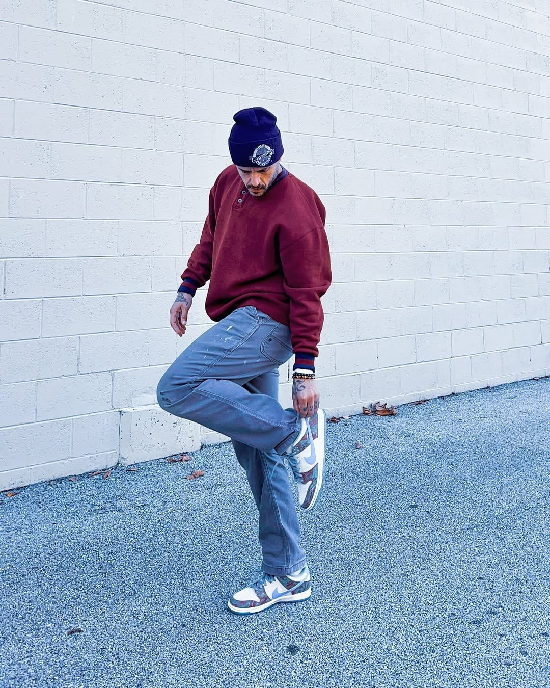 man wearing a black cherry henley with carpenter pants, and nike sneakers