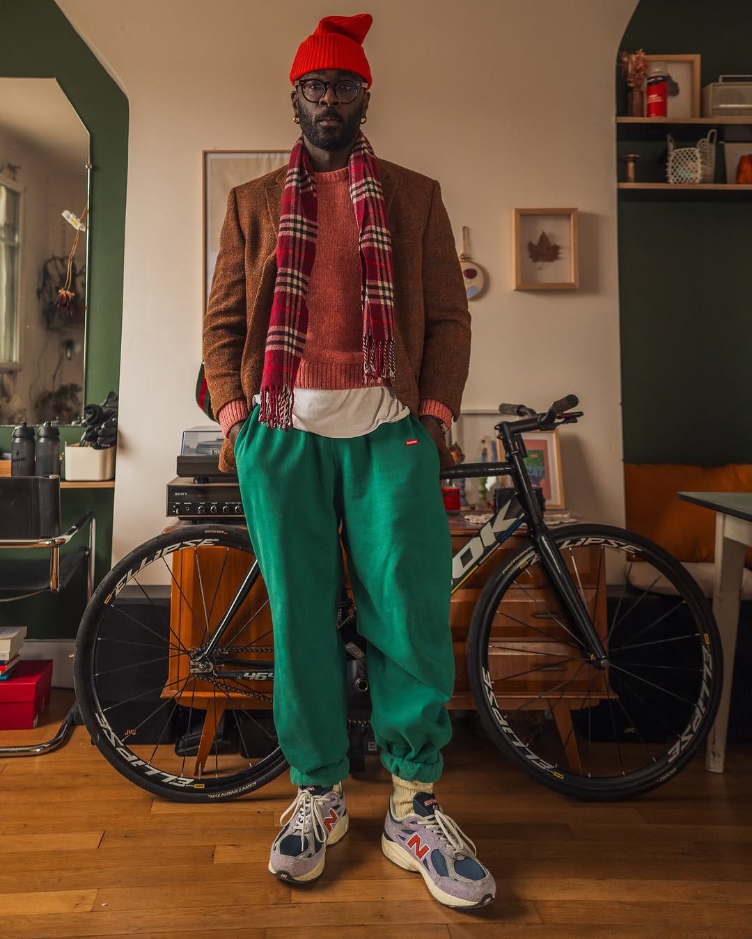 stylish man wearing green sweatpants, a red sweater, and a plaid scarf