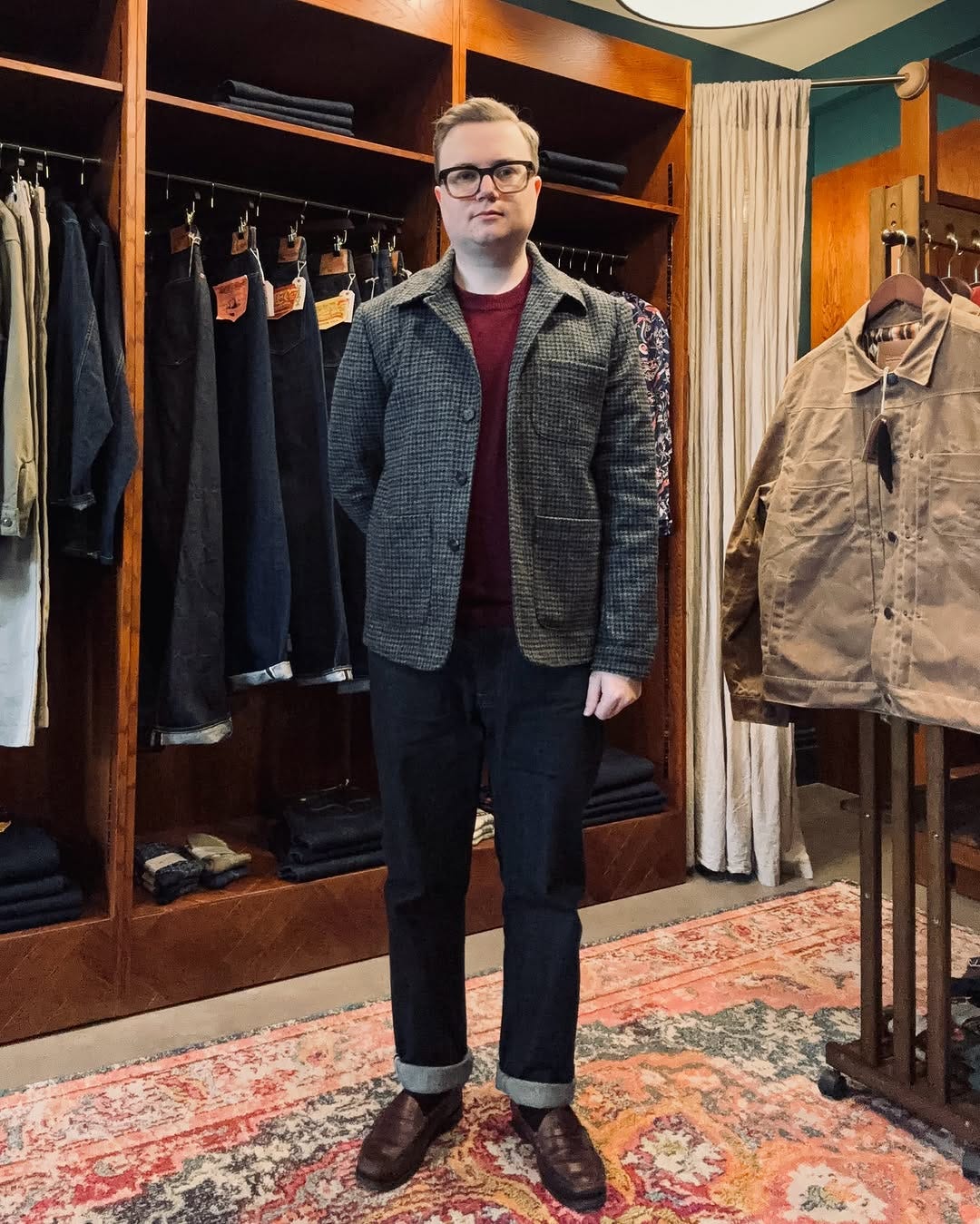 stylish man standing in a menswear store wearing a black cherry sweater and dark pants