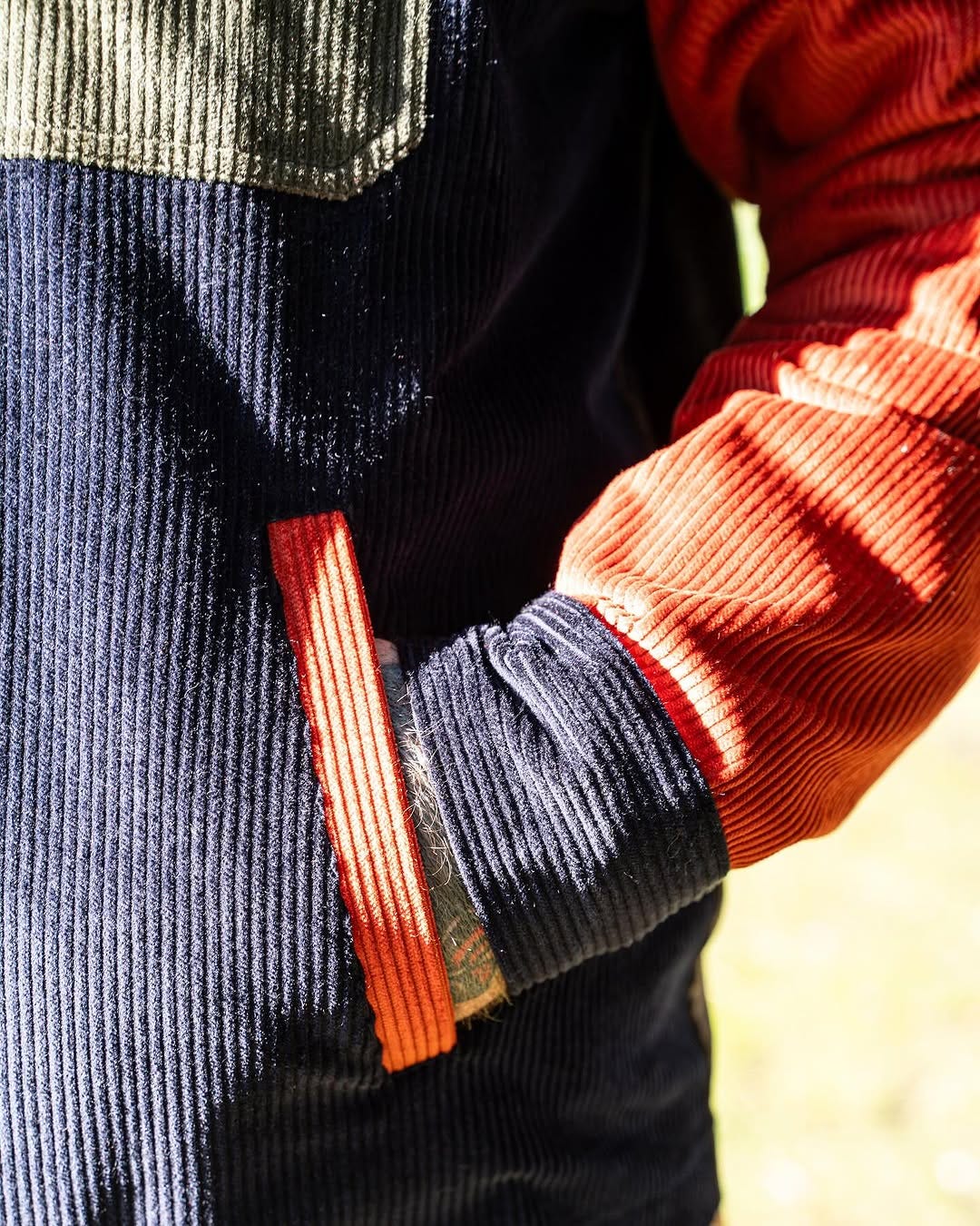 closeup of a man wearing a navy, orange, brown, and green corduroy shirt jacket 