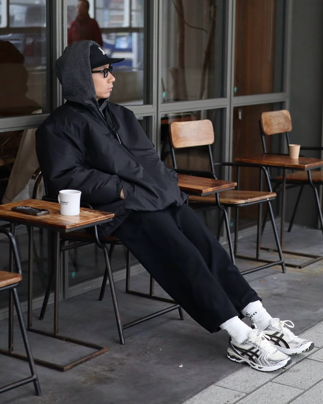 stylish man wearing an all-black outfit with asics sneakers