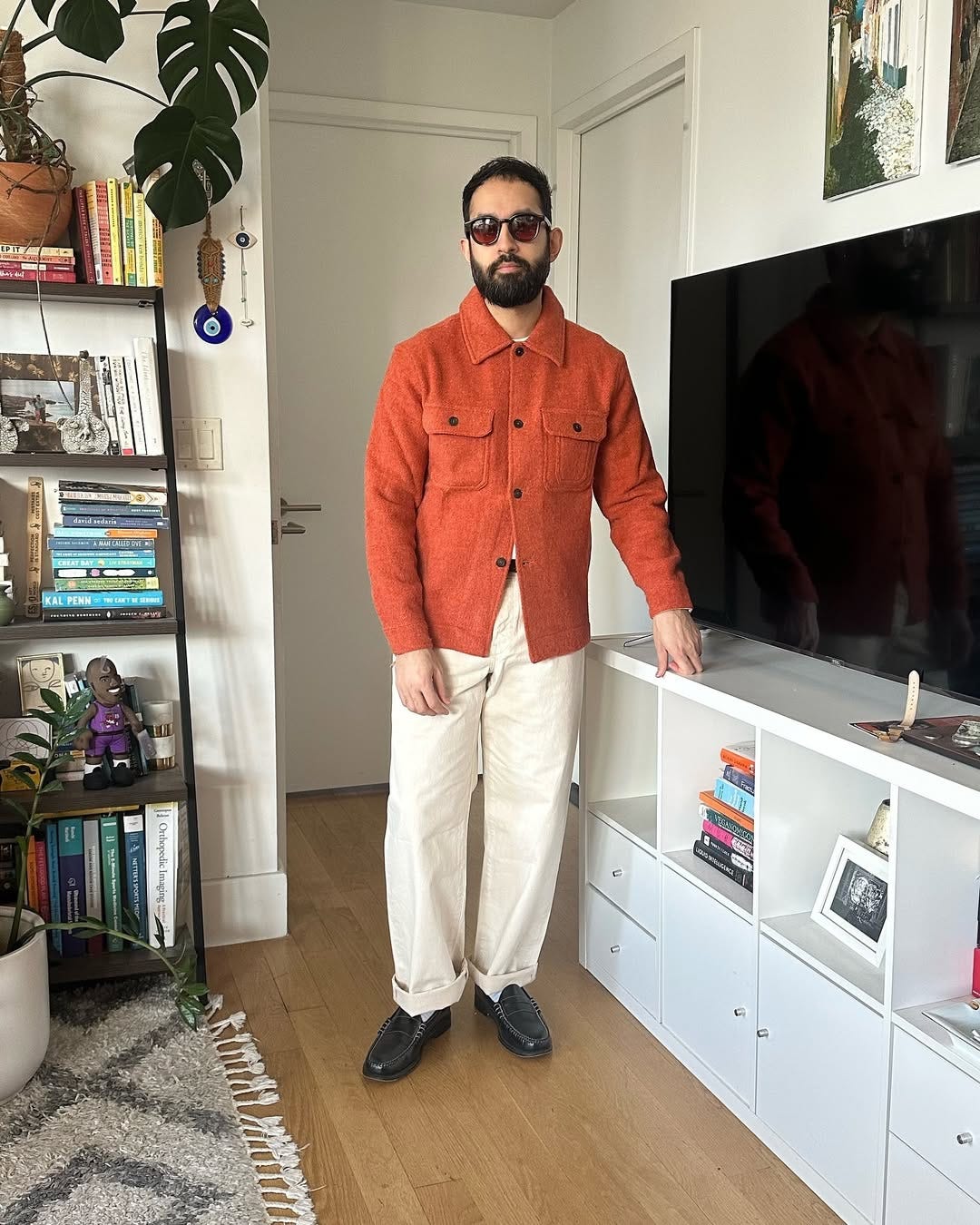 stylish man wearing an orange overshirt with off-white carpenter pants and black penny loafers