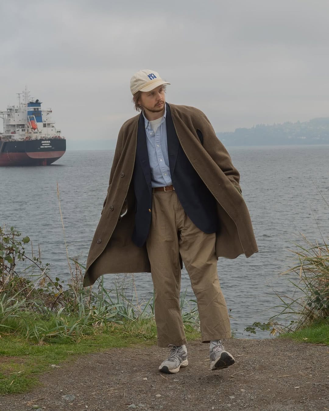 stylish man standing by the water wearing asics sneakers with a business casual outfit