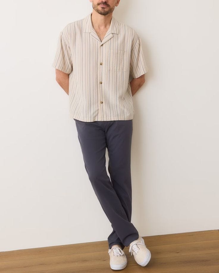 man wearing an off-white camp shirt with dark pants and white sneakers