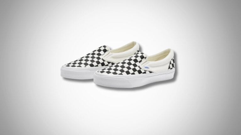 a pair of men's checkerboard black and white slip-on vans set against a grey background