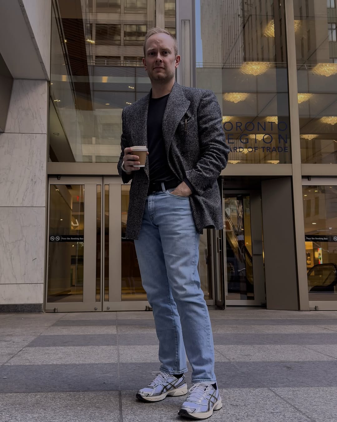 stylish man wearing jeans and a textured overcoat with asics sneakers