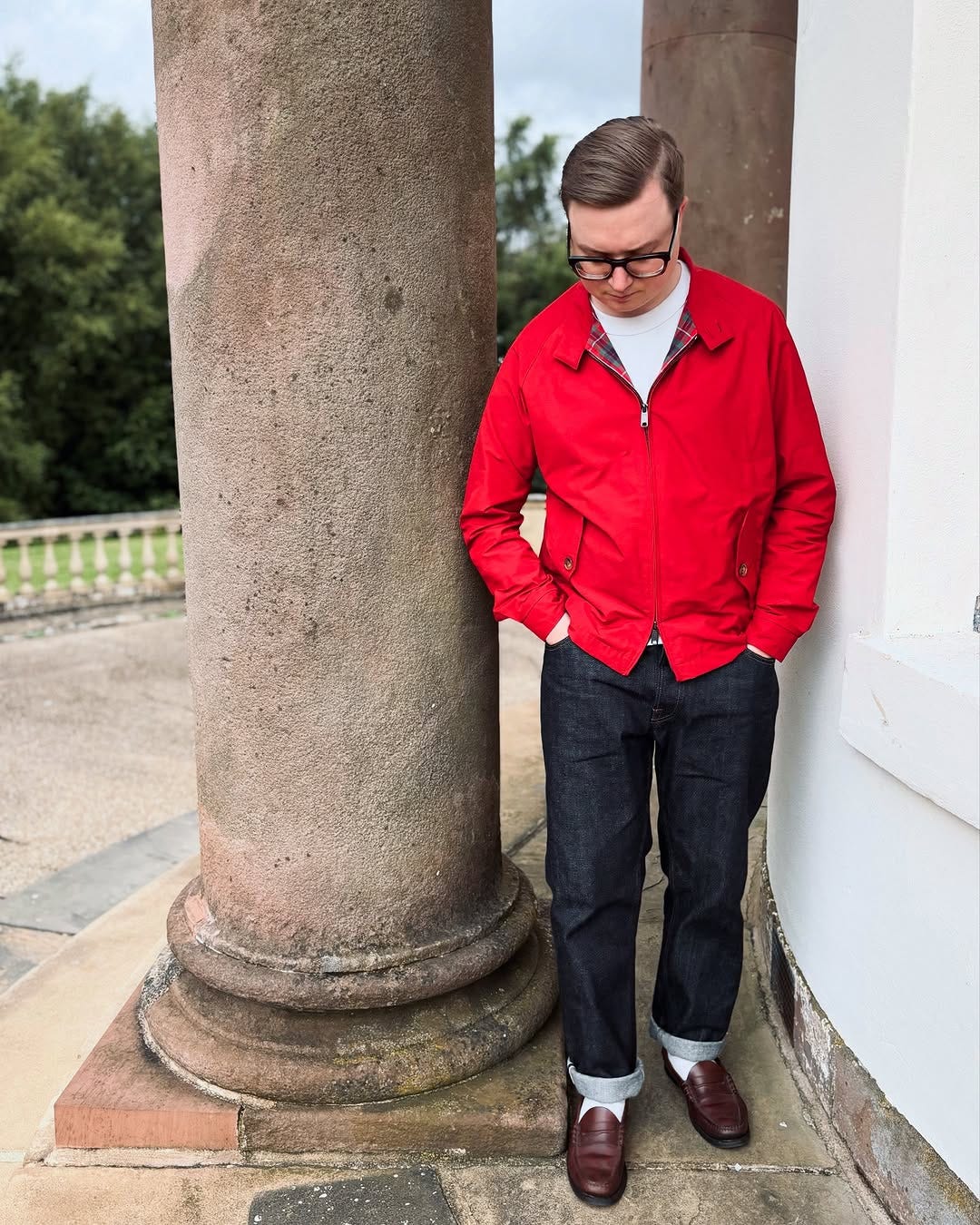 stylish young man wearing a red baracuta harrington jacket with dark blue jeans, brown penny loafers, and white socks