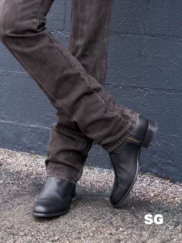 man from the knees down wearing black jeans and black cowboy boots