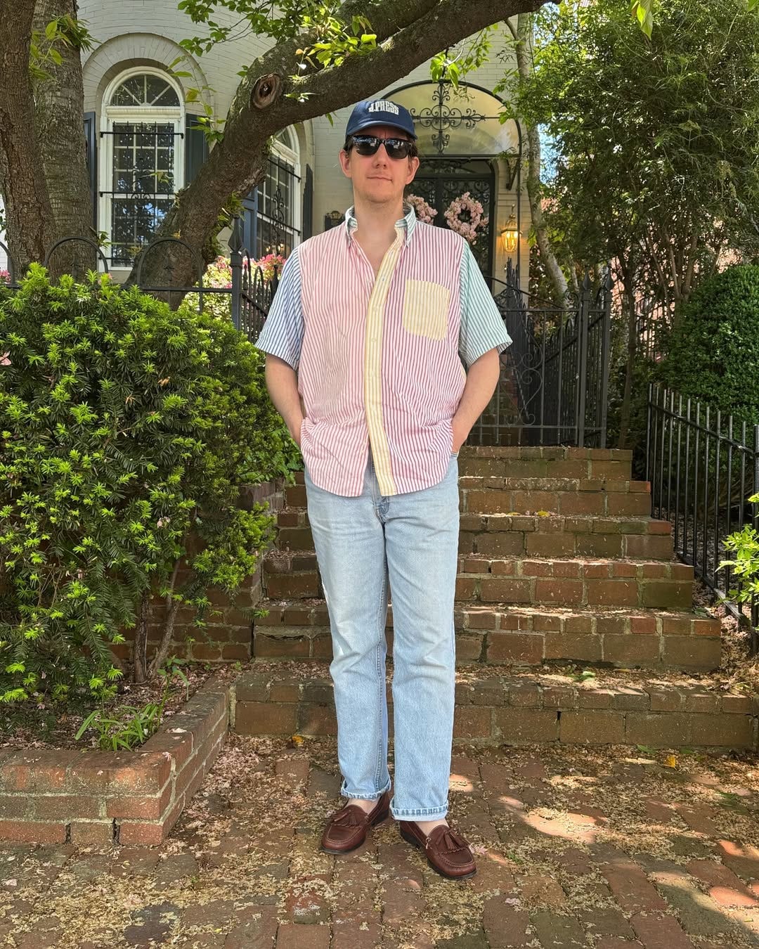 stylish man wearing a preppy striped short-sleeve shirt with light wash jeans and brown leather slip-on shoes