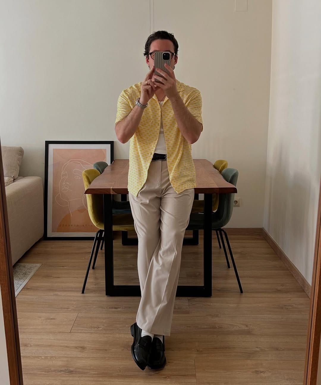 stylish man wearing a yellow textured short-sleeve shirt over a white tank with tan pants and a braided leather belt