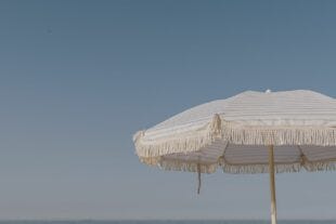 faded image of a beach umbrella against a blue sky
