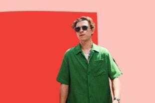 image of tom holland wearing a short-sleeve green shirt and sunglasses against a pink and red abstract background