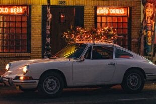 vintage car with a lit-up christmas tree on the top in front of a bar