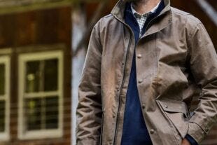 close-up of a man wearing a waxed canvas jacket over a navy sweater