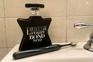 bottle of fragrance sitting on a bathroom sink next to a toothbrush