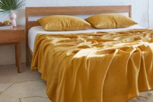 light wood bedframe with yellow sheets and pillows