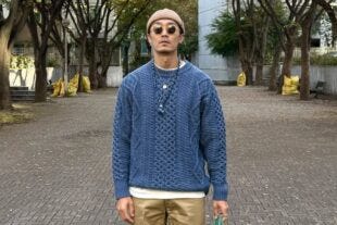 stylish man wearing a beanie, sunglasses, blue fisherman sweater, and tan chinos